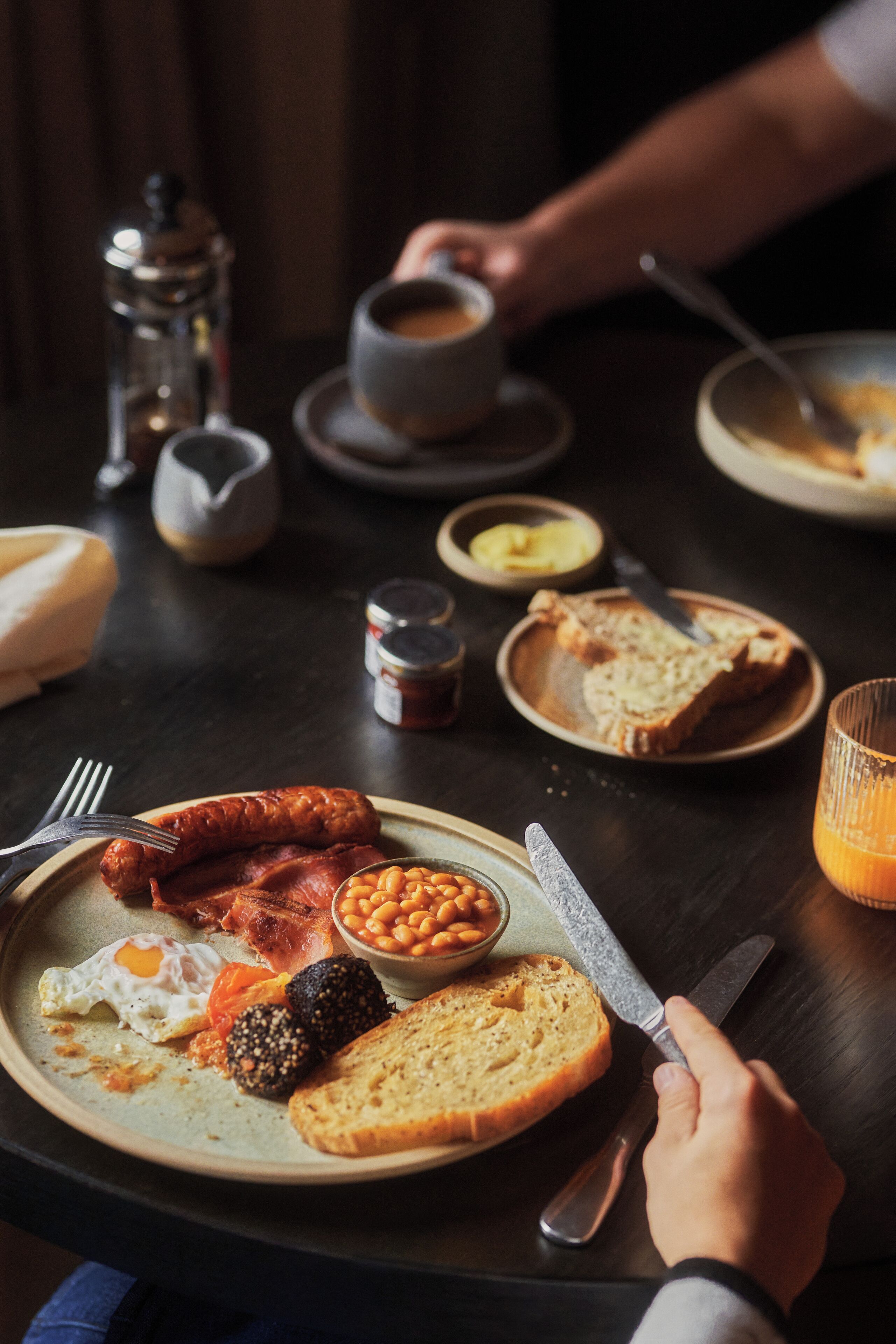 Une assiette de petit-déjeuner comprenant des saucisses, des œufs, des haricots et des toasts.