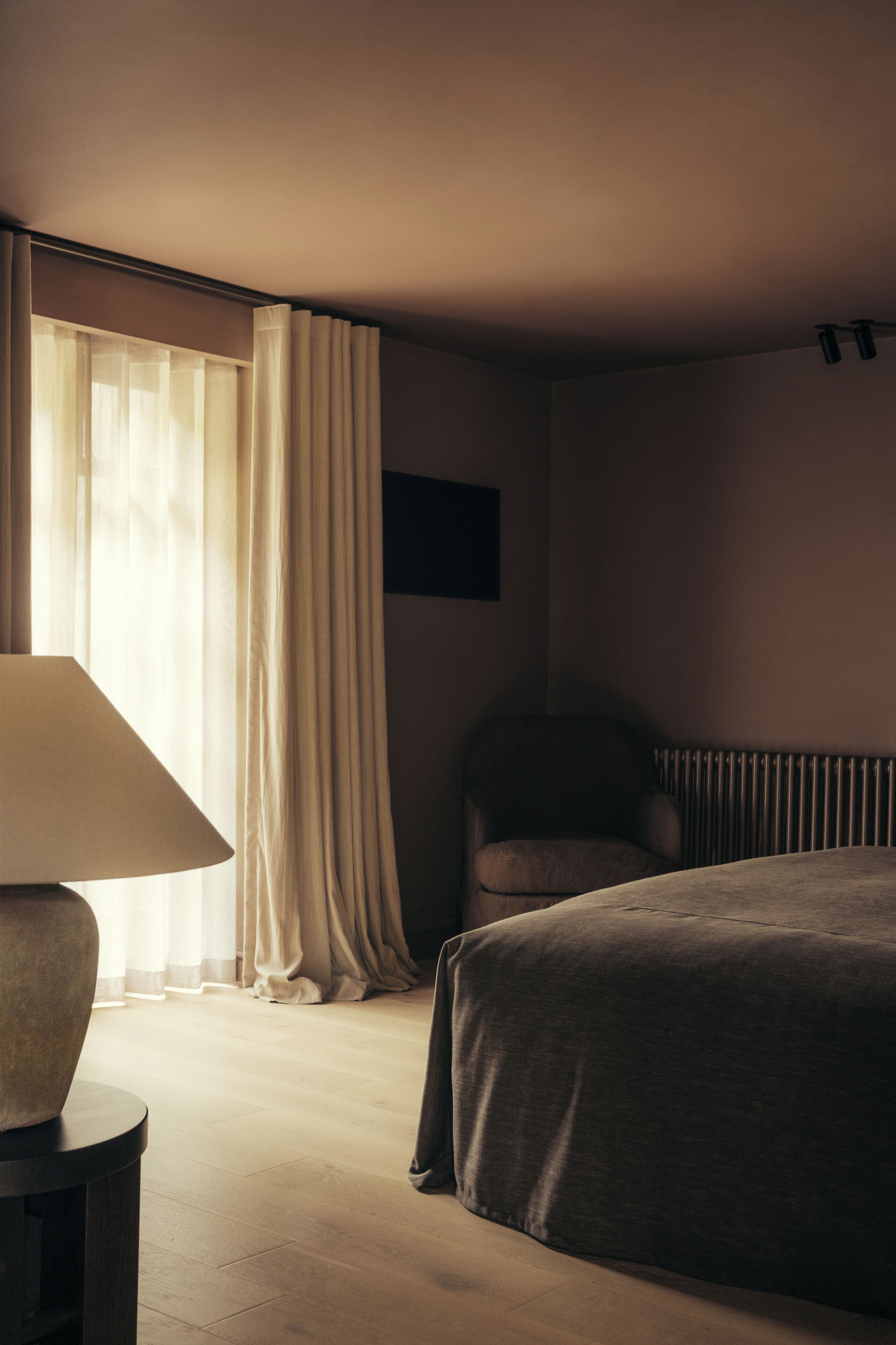 Ein Hotelzimmer mit Bett, Stuhl, Lampe und Heizkörper.