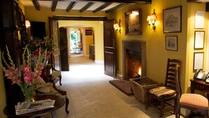 A cozy lobby with a fireplace, wooden furniture, and a vase of flowers.