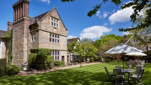A stone building with a large lawn and outdoor seating area.