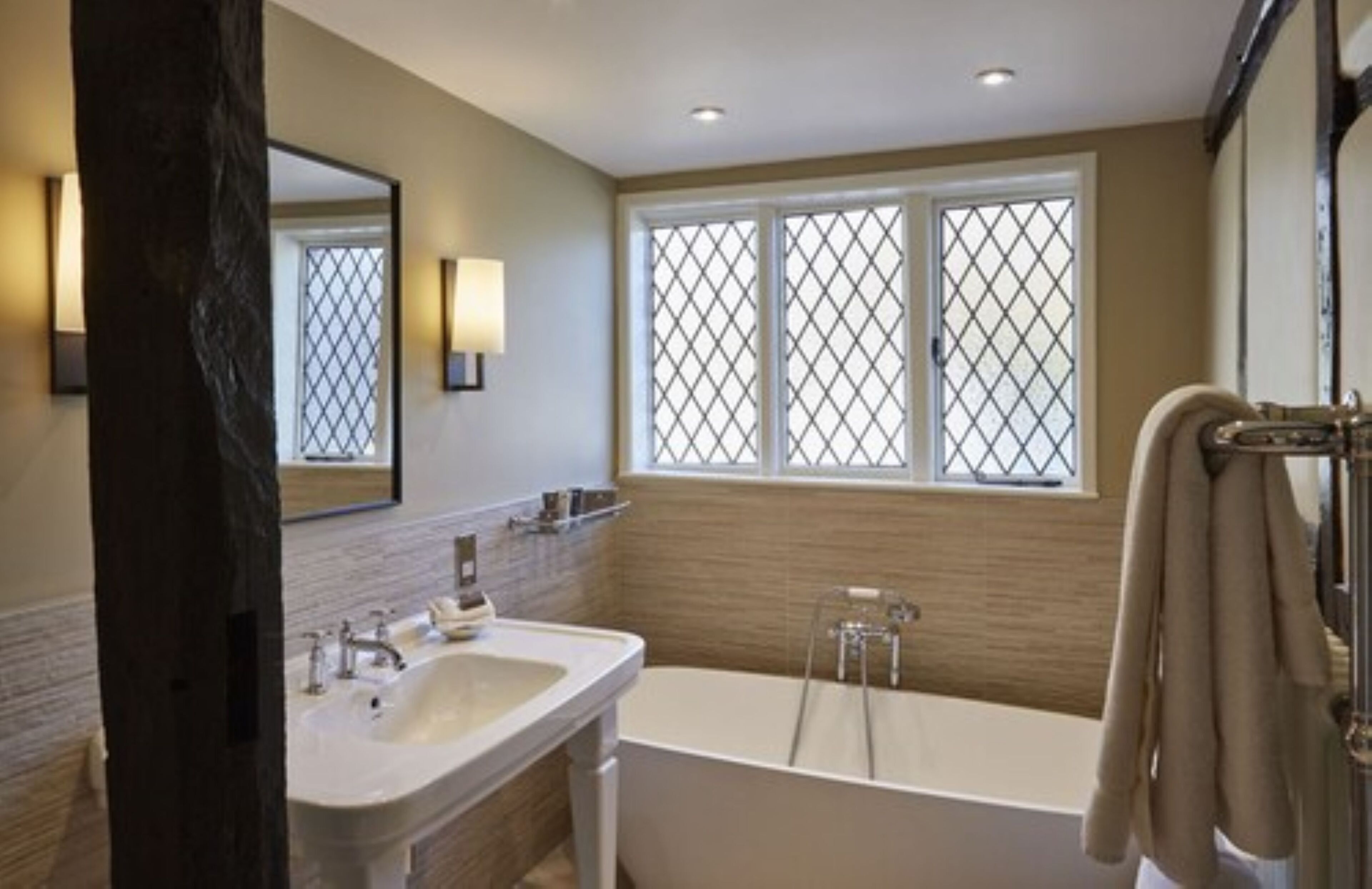 A modern bathroom with a double sink, a bathtub, and a large mirror.