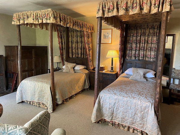 A traditional four-poster bed with floral curtains, a bedside lamp, and a framed picture on the wall.
