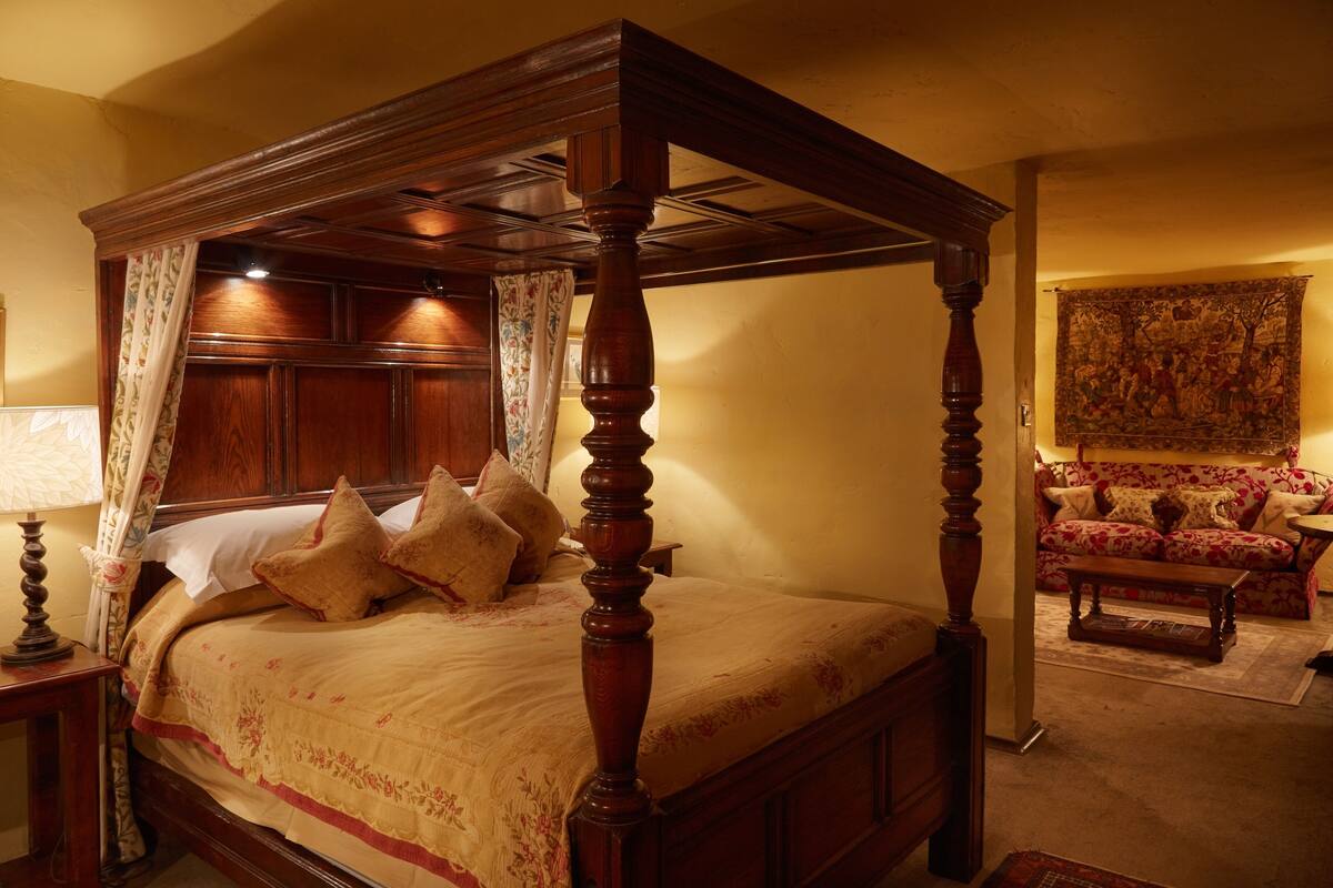 Un lit à baldaquin, un canapé à motifs floraux et une tapisserie au mur.