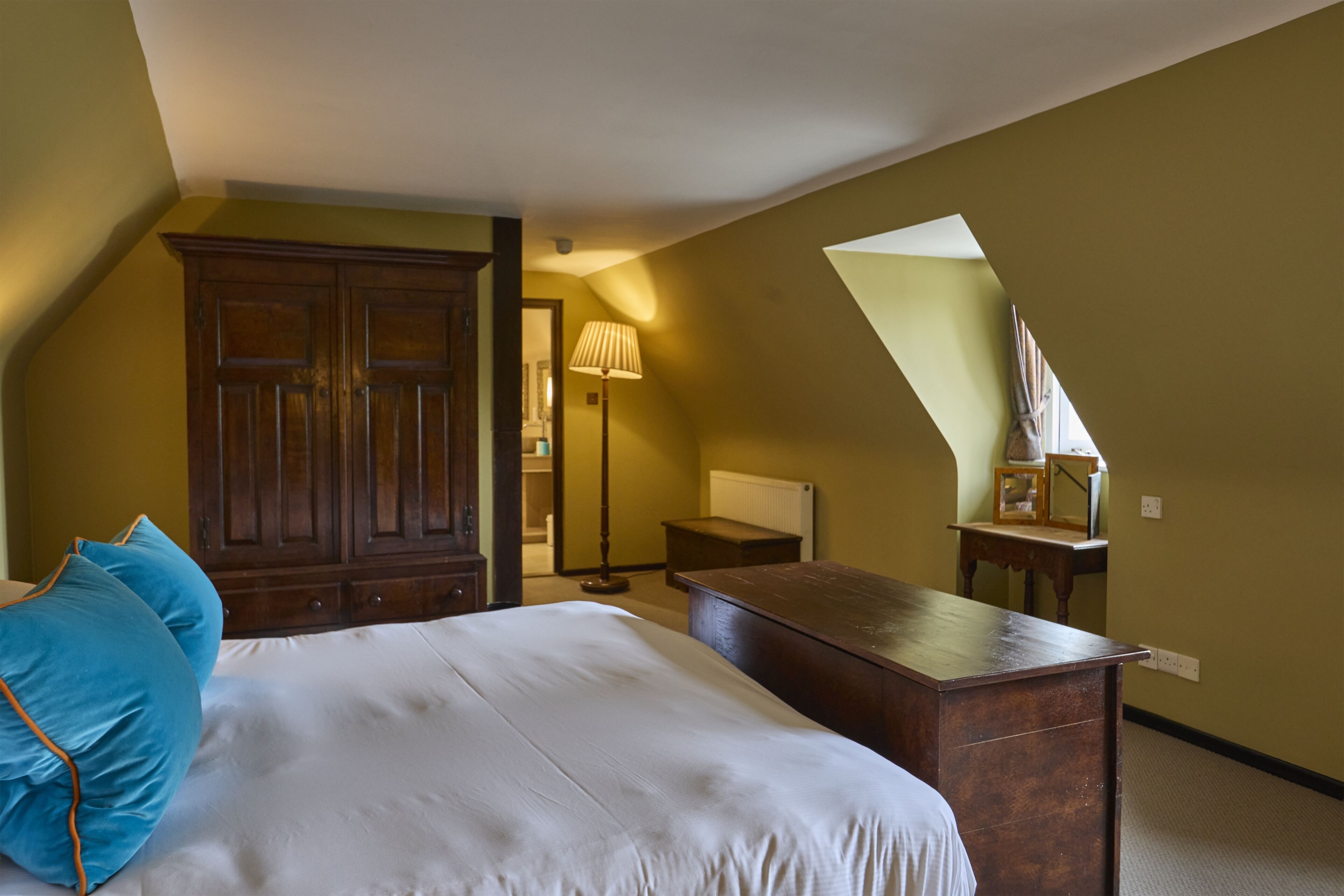 A bedroom with a bed, a dresser, a lamp, and a mirror.