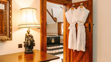 A wooden door with two white robes hanging on hooks, a statue on a table, and a lamp with a white shade.