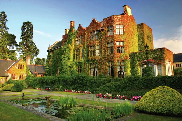A large ivy-covered building with a formal garden, including a pond and well-manicured lawns. - Pennyhill Park (Bagshot)