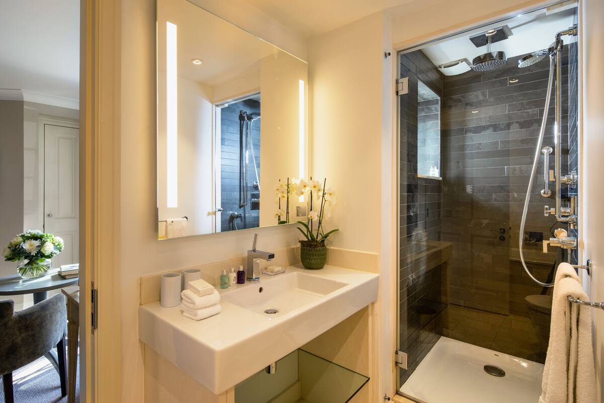 A modern bathroom with a glass-enclosed shower, a large mirror, and a vanity with a sink and towel rack.