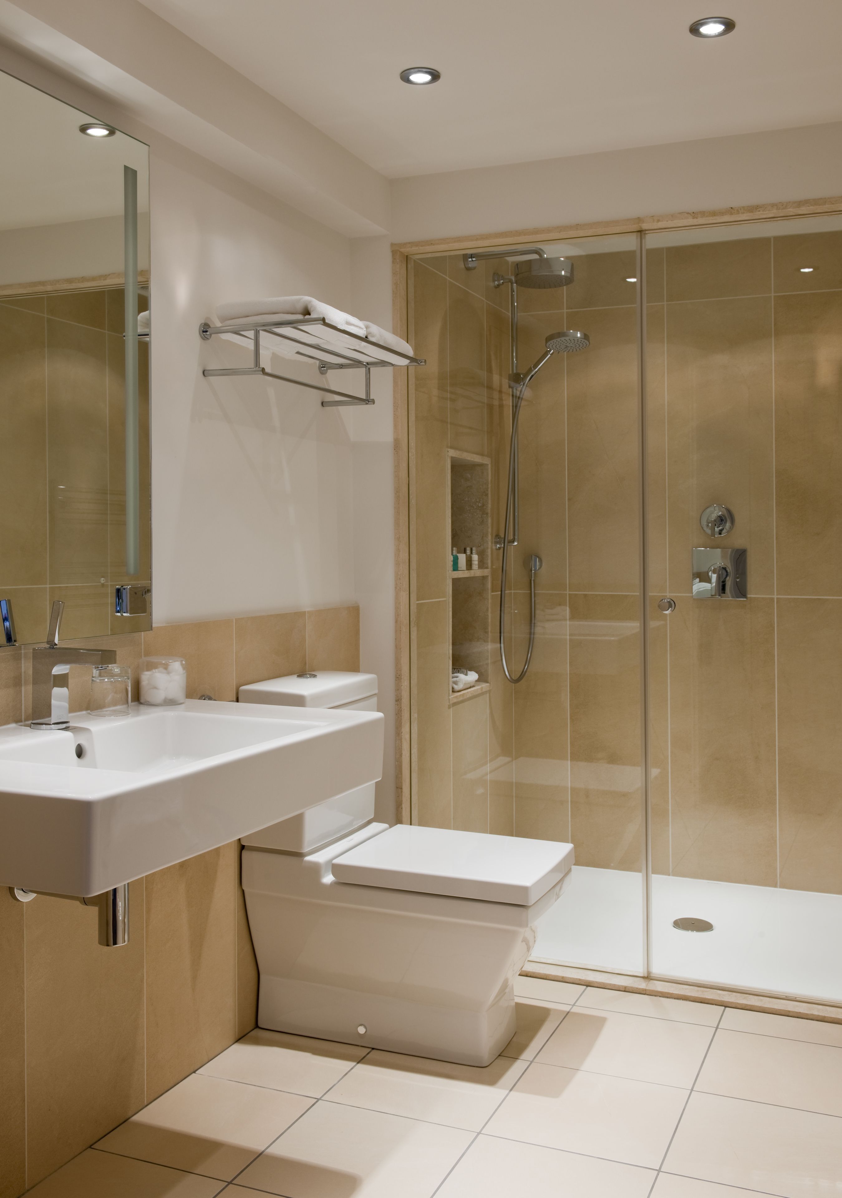 A modern bathroom with a glass-enclosed shower, a white sink, and a large mirror.