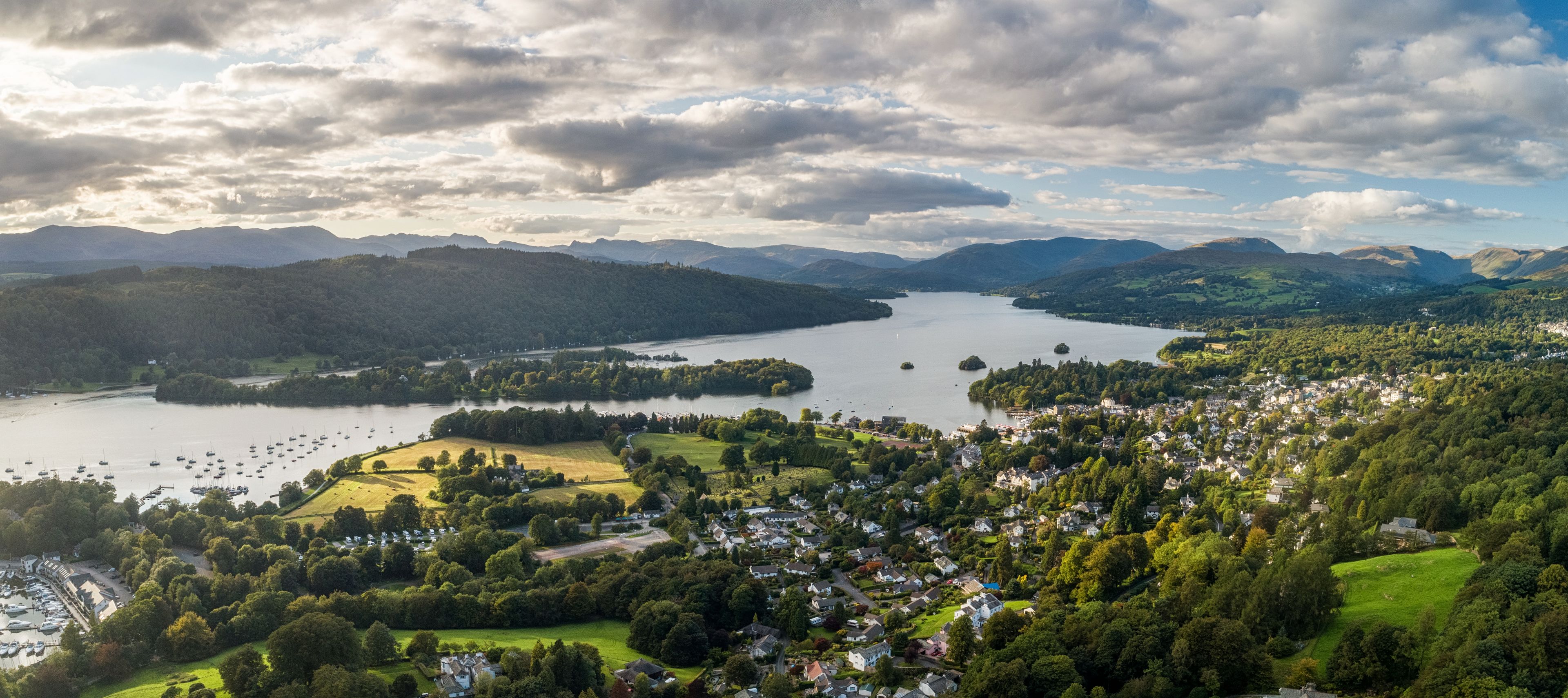 Vista panorámica de un pueblo a orillas del lago, con zonas residenciales, un puerto deportivo y colinas circundantes.