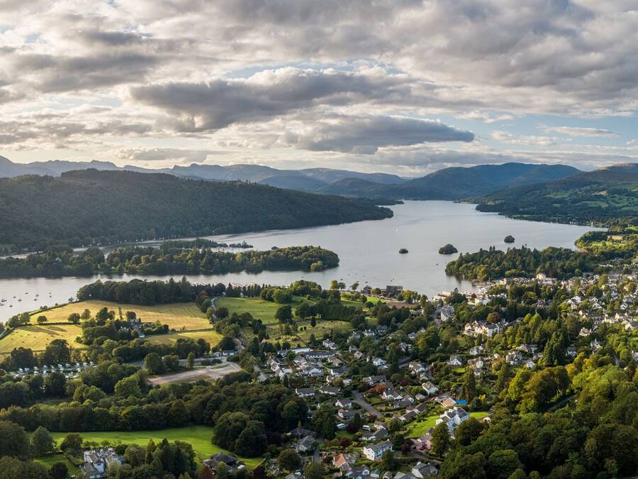 Vista panorámica de un pueblo a orillas del lago, con zonas residenciales, un puerto deportivo y colinas circundantes.