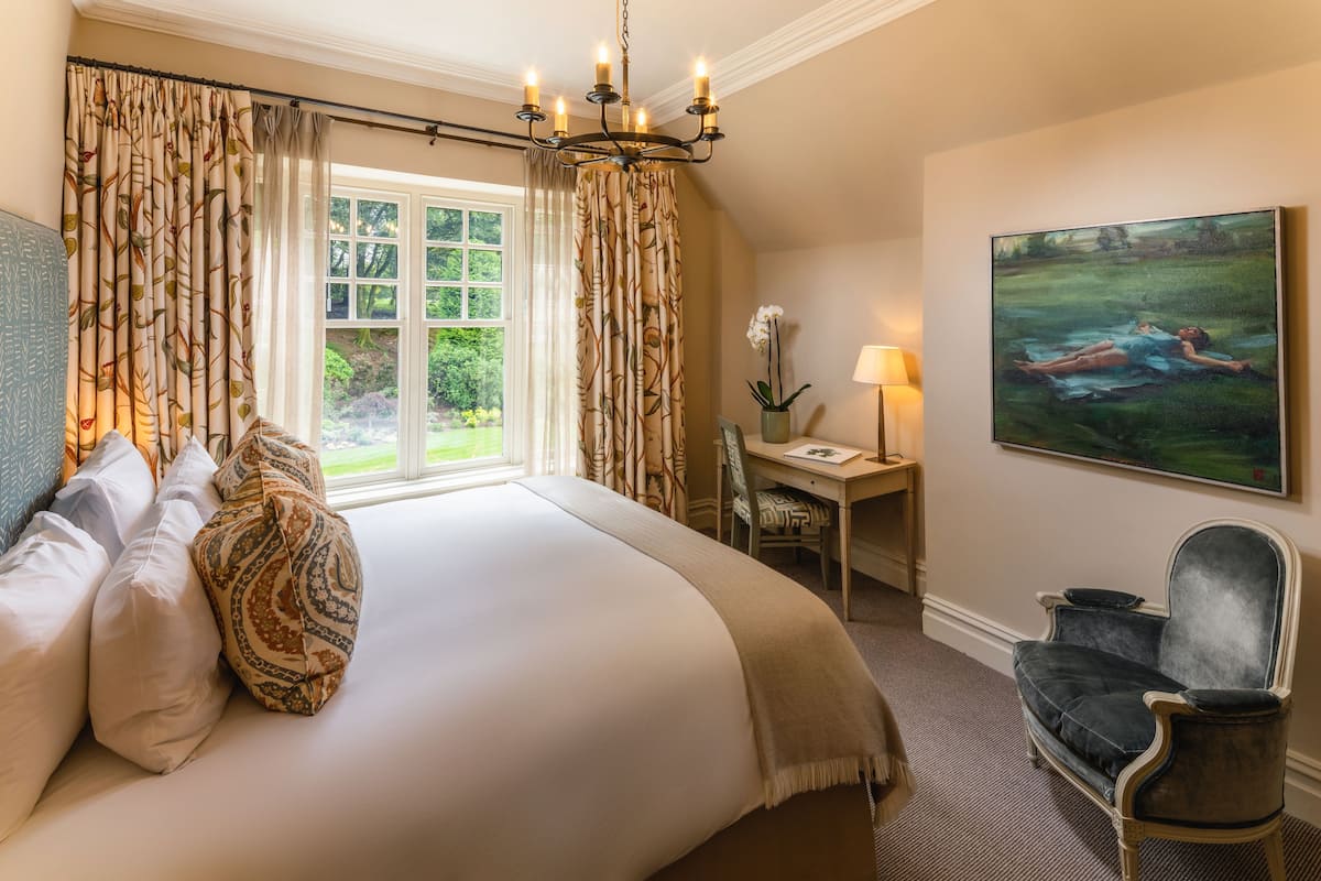 A bedroom with a large bed, a desk, a chair, and a painting on the wall.