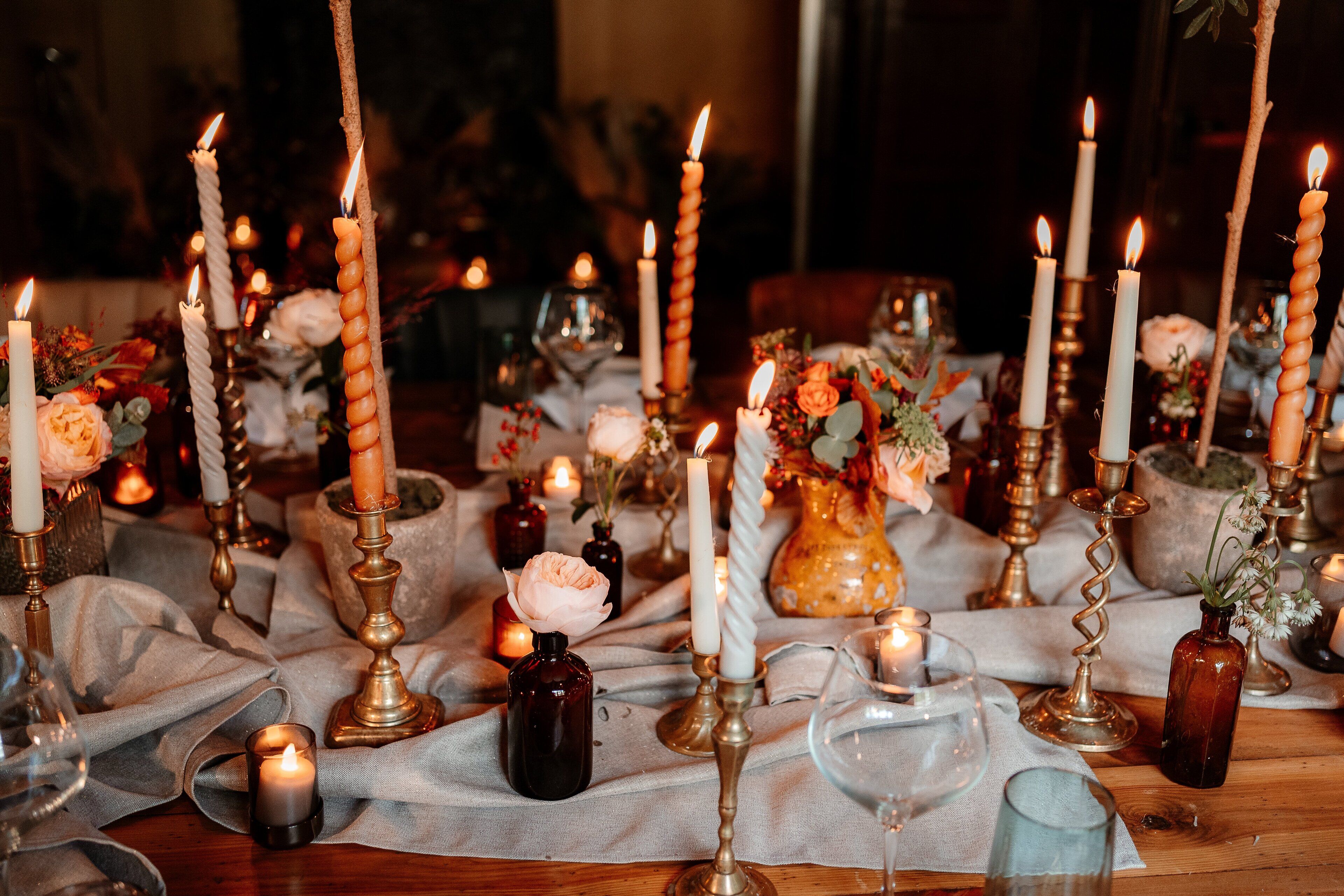 Une table dressée avec des bougies, des vases et de la verrerie, ce qui laisse supposer qu’il s’agit d’un dîner ou d’un événement formel.