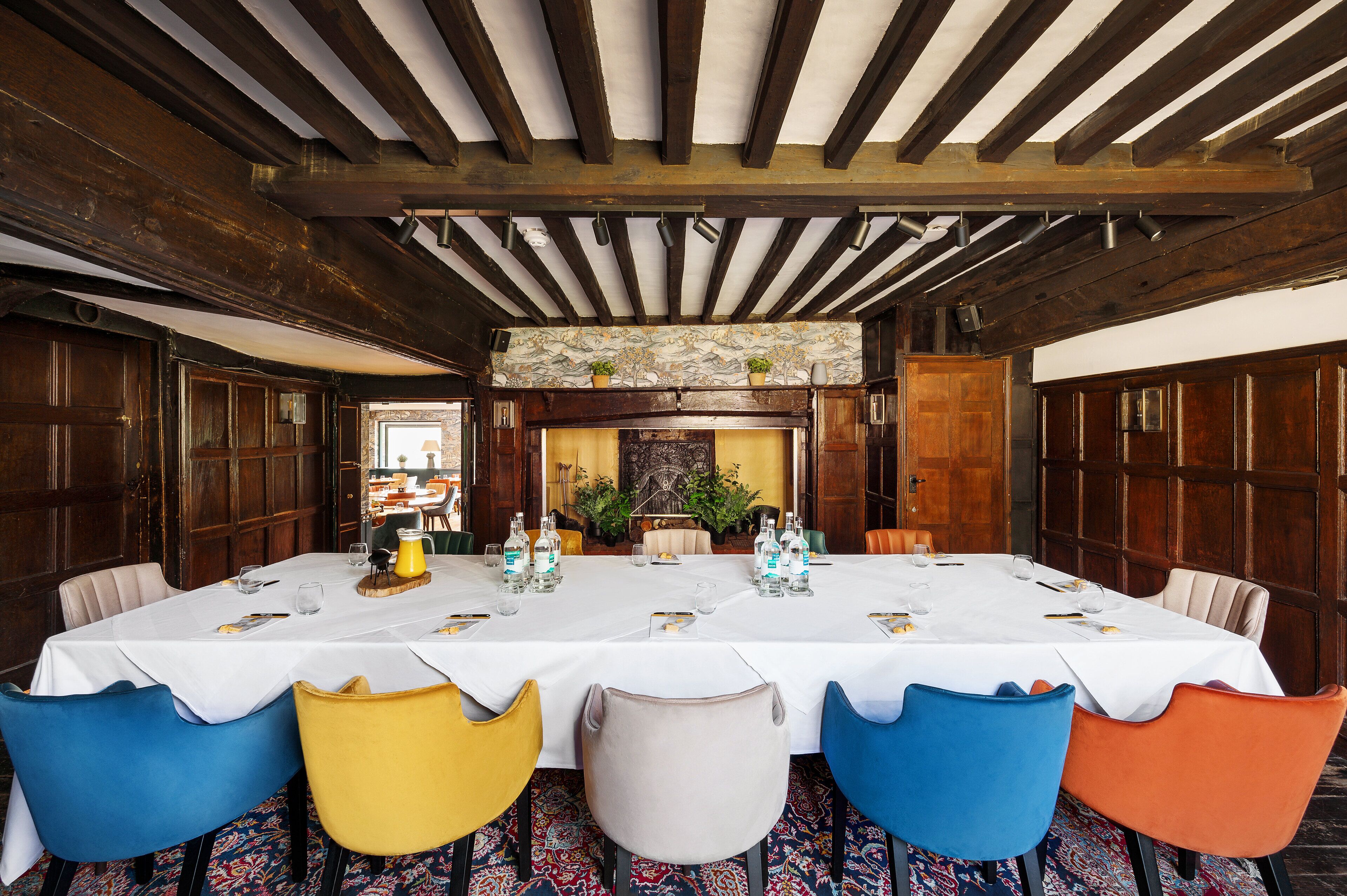 A dining area with a long table set for a meal, surrounded by wooden walls and a stone fireplace.