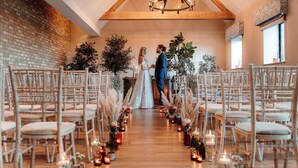A wedding aisle with white chairs, candles, and floral arrangements. - voco Lythe Hill Hotel & Spa by IHG (Haslemere)