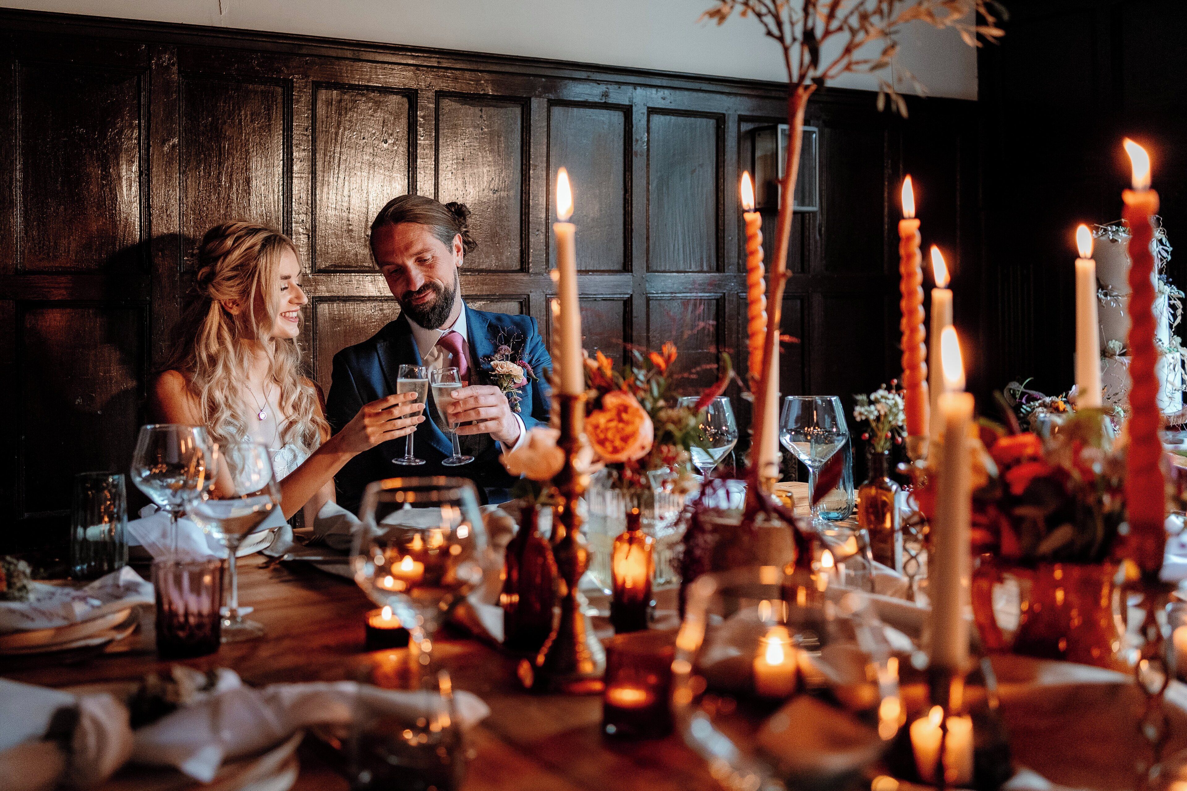 Una pareja sentada en una mesa con velas, copas de vino y flores.