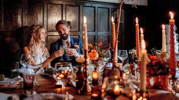 Una pareja sentada en una mesa con velas, copas de vino y flores.