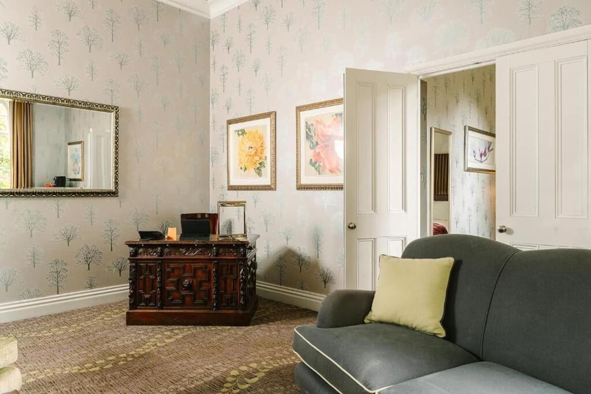 A room with a dark green sofa, a wooden cabinet, and framed pictures on the wall.