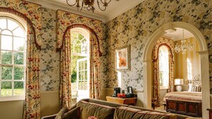 A room with a sofa, a bed, a chandelier, and floral wallpaper. - Lainston House Hotel (Winchester)