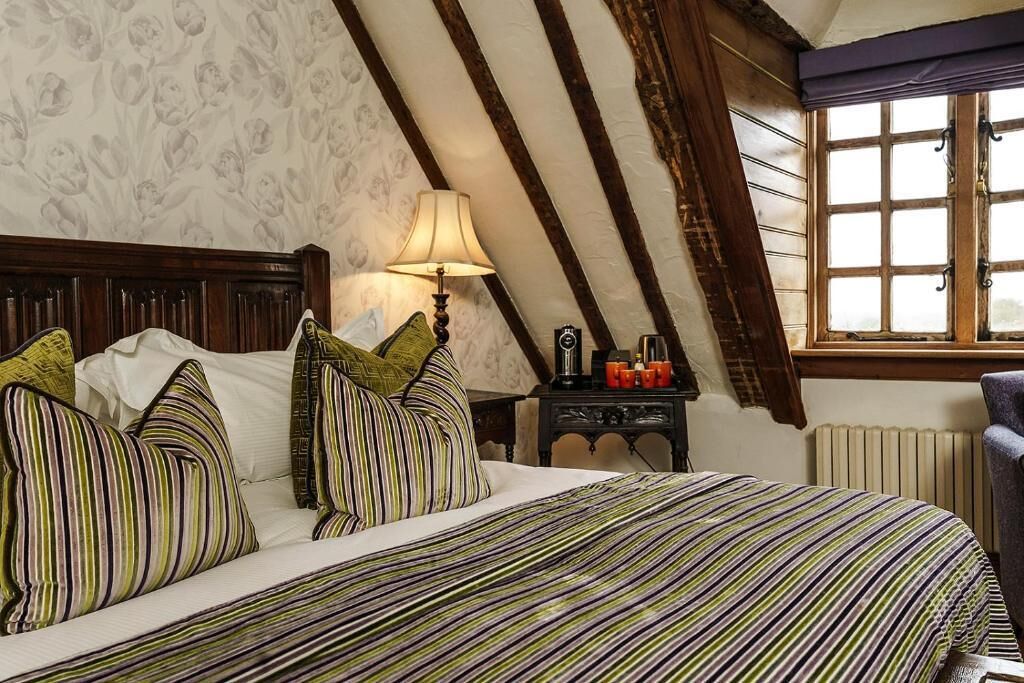 Une chambre avec un lit, une table de chevet, une lampe et une fenêtre.