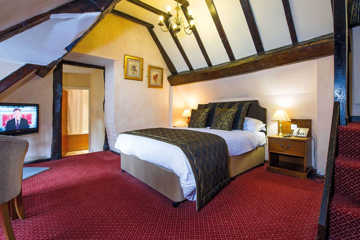 A bedroom with a large bed, a television, and a wooden nightstand.
