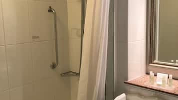 A bathroom with a walk-in shower, a sink, and a mirror.
