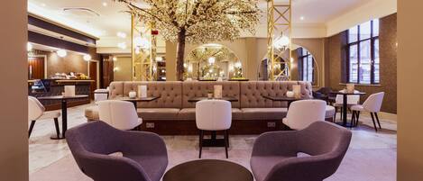 A modern lounge area with a sofa set, two armchairs, and a round table.