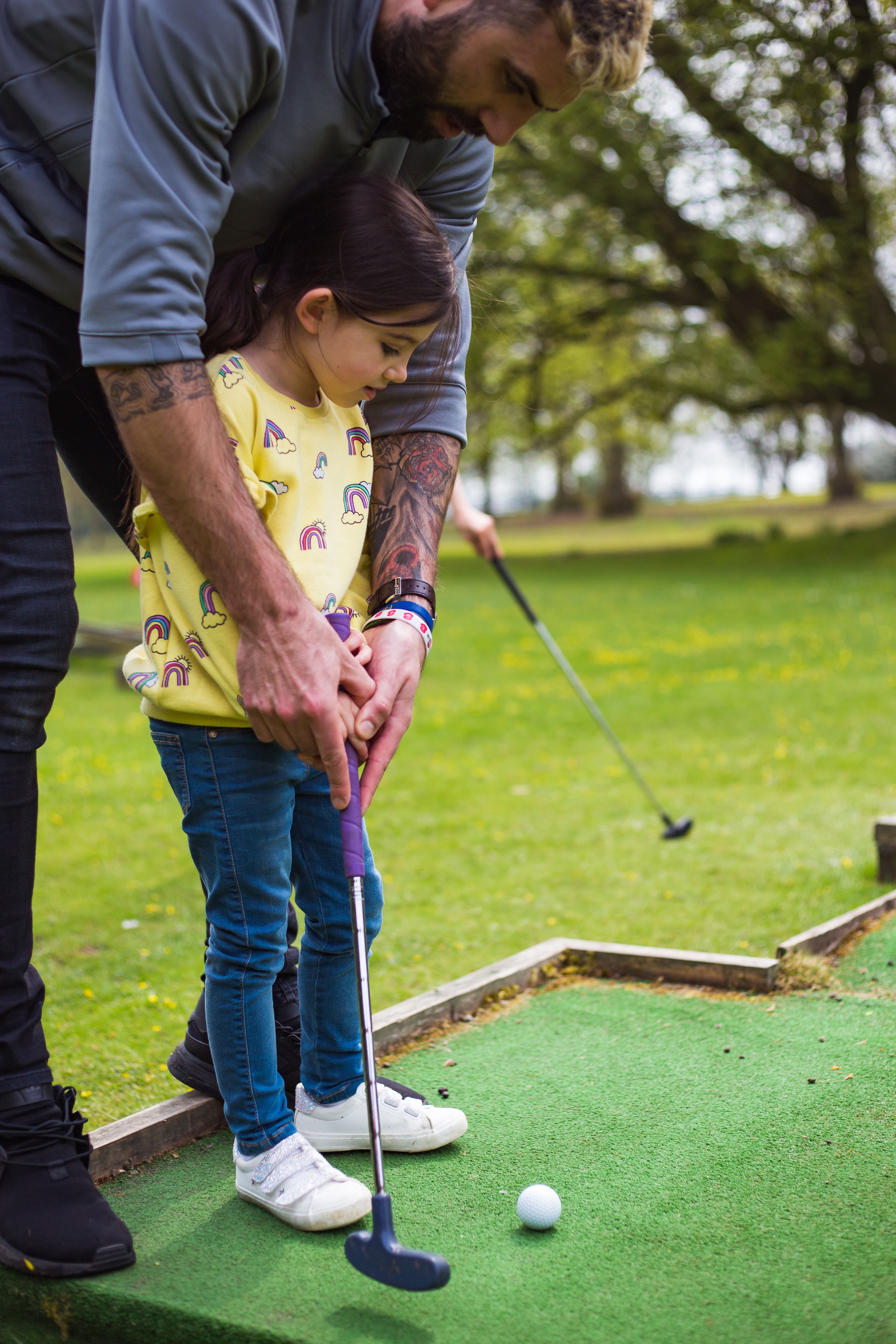 Una persona y un niño jugando al golf en un campo verde.