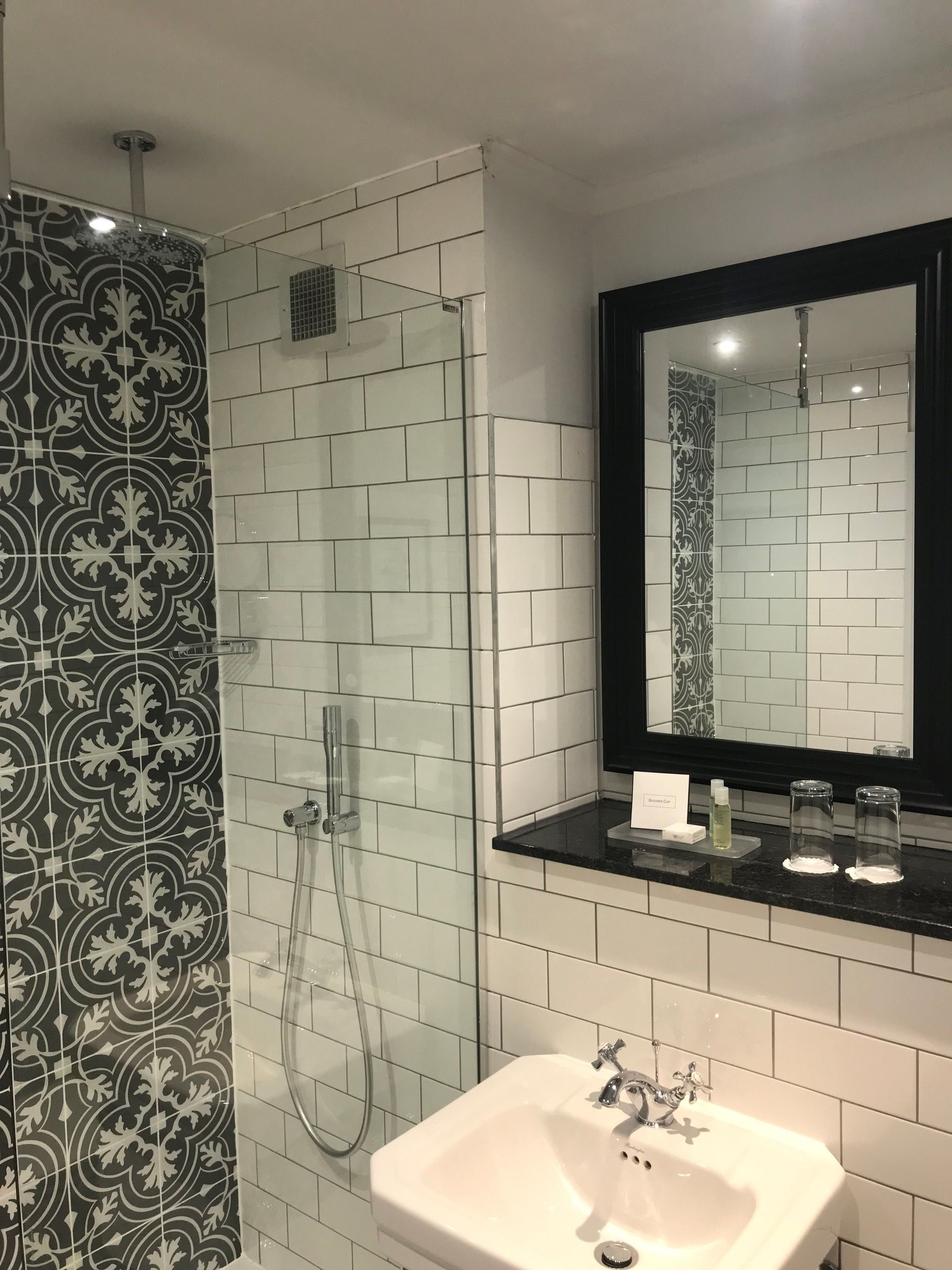 Un baño con ducha, lavamanos y espejo.