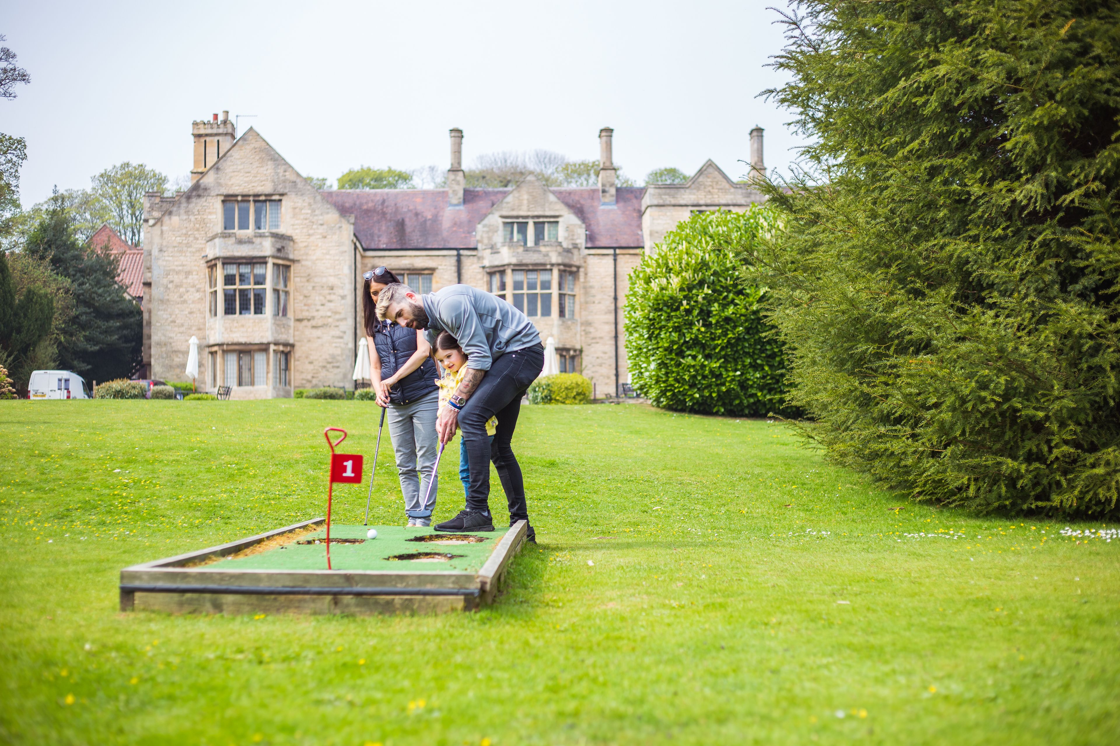 A croquet game on a grassy lawn with a historic building in the background.