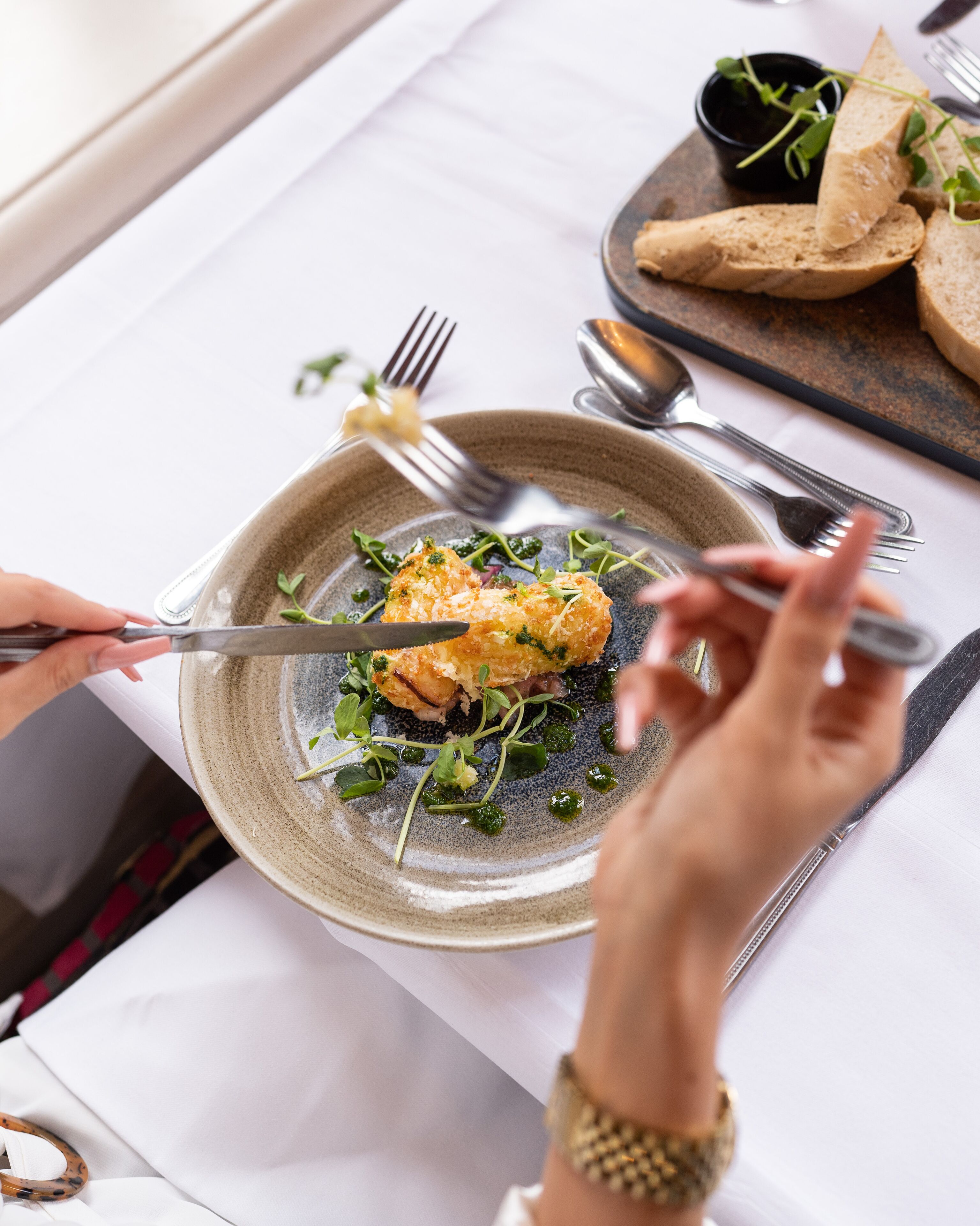 Ein Esstisch mit einem Teller Essen, Besteck und einem Smartphone.