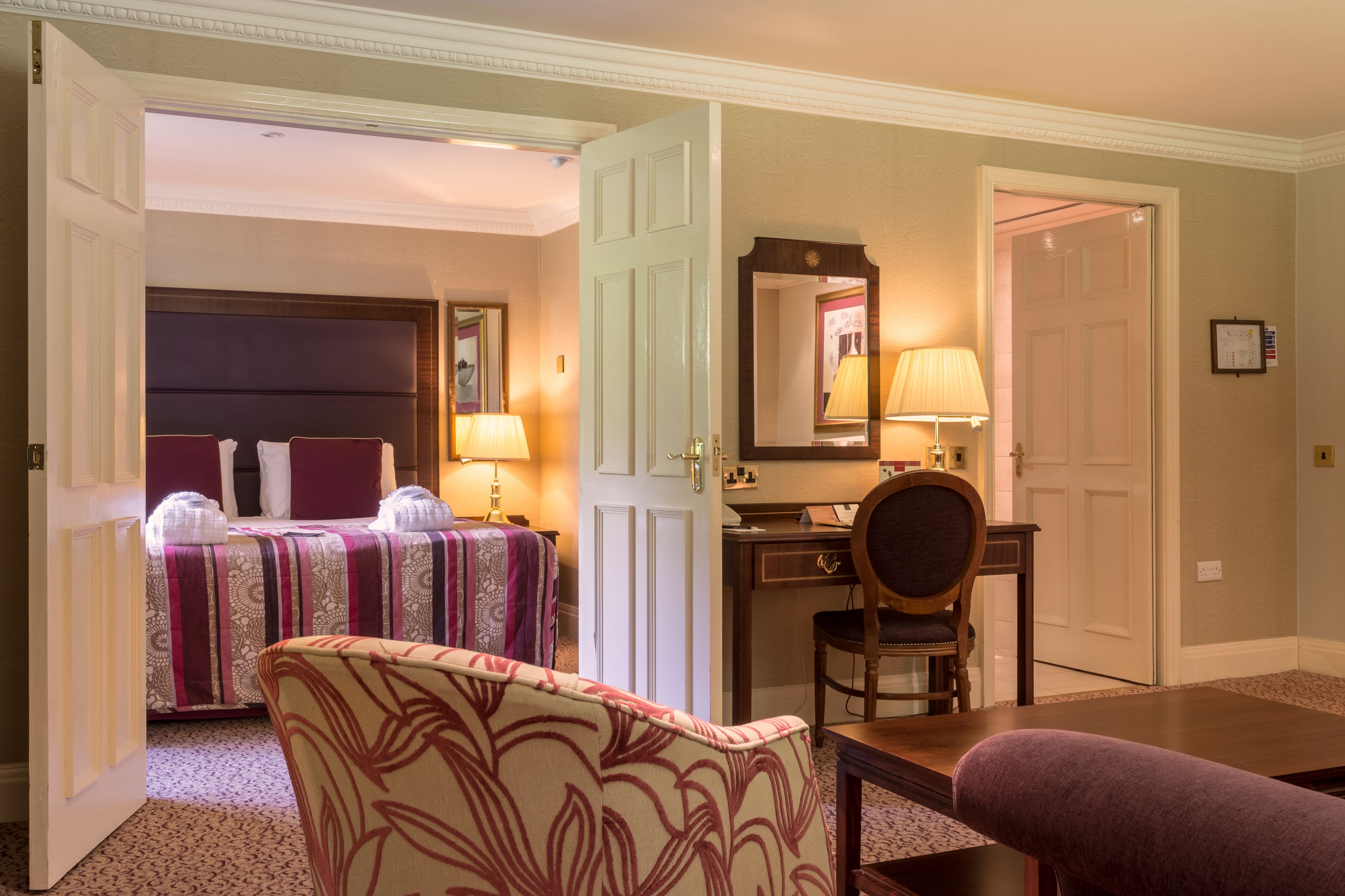 A hotel room with a bed, a desk, a chair, and a table.