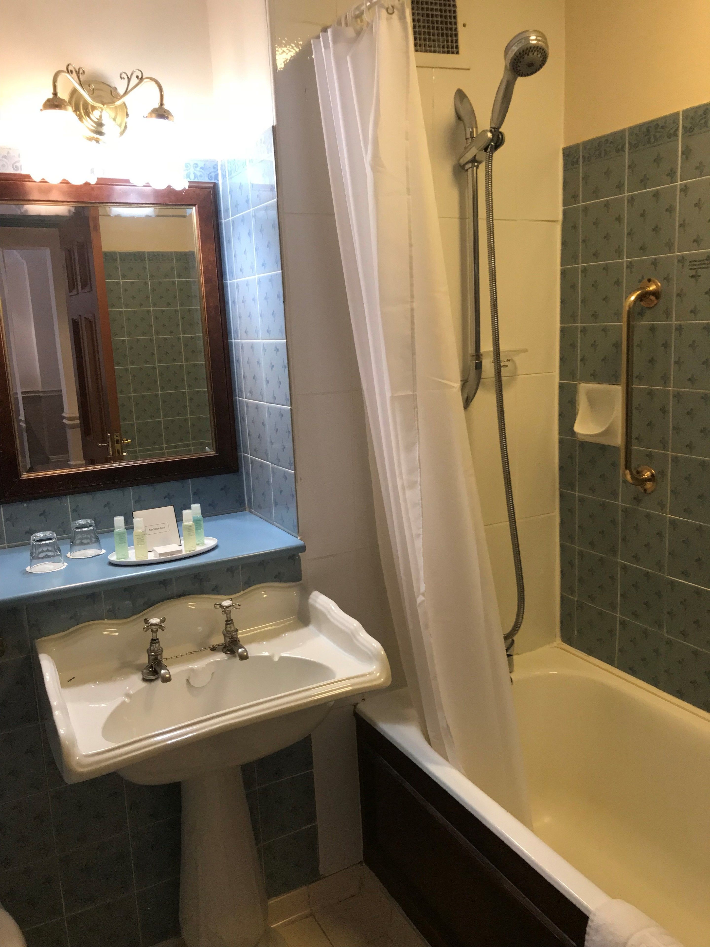 A bathroom with a sink, mirror, shower, and a towel rack.