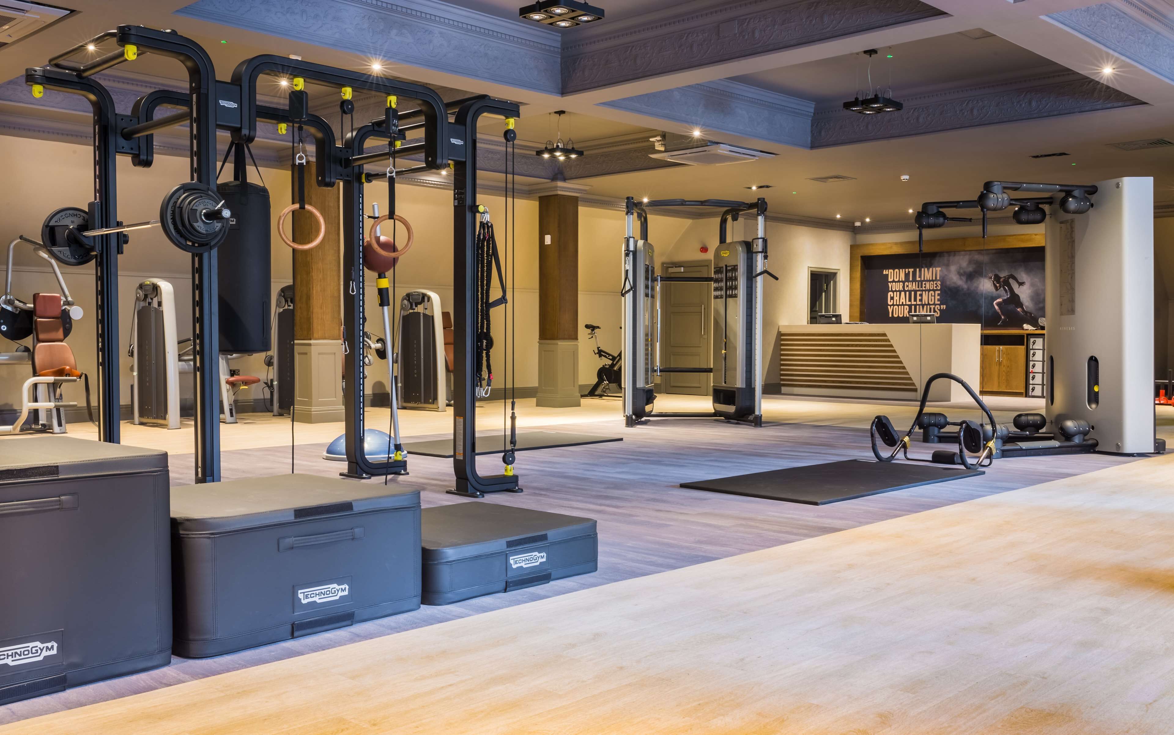 A modern gym with various exercise equipment, including weight machines, a pull-up bar, and a stationary bike.