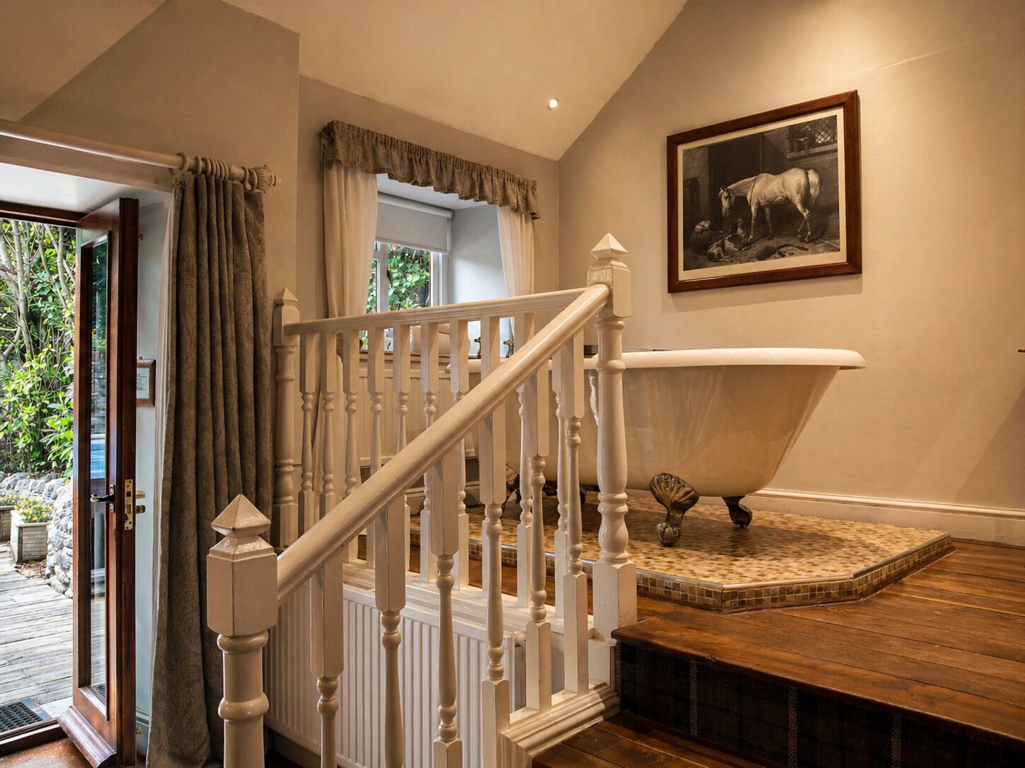 A staircase with white balusters, a bathtub, and a framed picture of a cow on the wall.