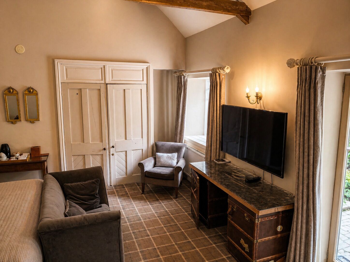Una habitación con una cama, un escritorio, una silla, un televisor y un armario.
