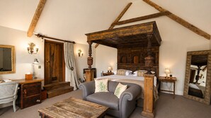 A bedroom with a four-poster bed, a sofa, a wooden coffee table, a dresser, and a mirror. - Montigo Resorts, Somerset (Shepton Mallet)