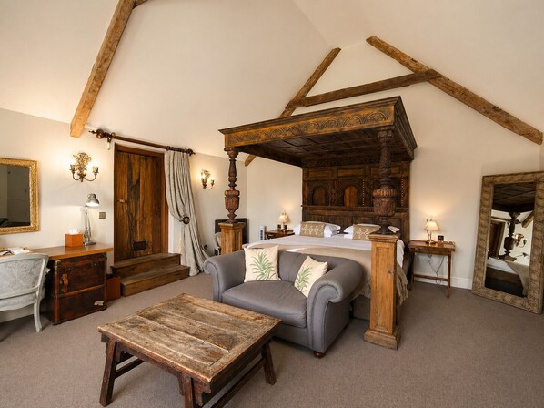 A bedroom with a four-poster bed, a sofa, a wooden coffee table, a dresser, and a mirror. - Montigo Resorts, Somerset (Shepton Mallet)