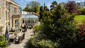 A stone building with a conservatory, outdoor seating, and a well-maintained garden. - Montigo Resorts, Somerset (Shepton Mallet)