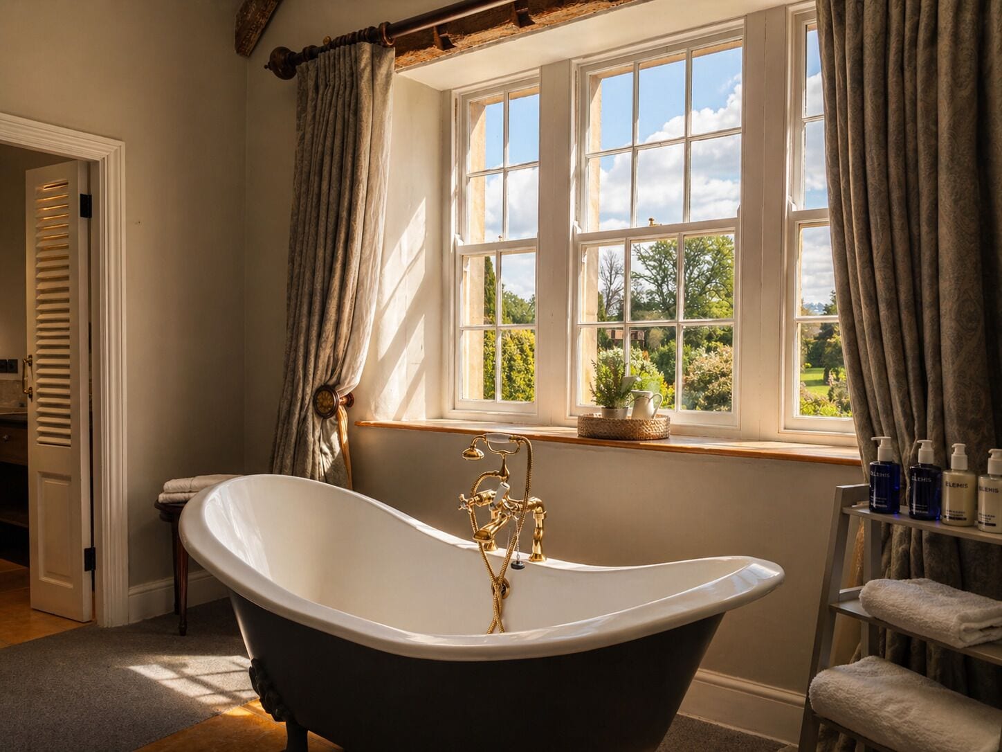 A bathroom with a freestanding bathtub, a window with curtains, and a shelf with toiletries.