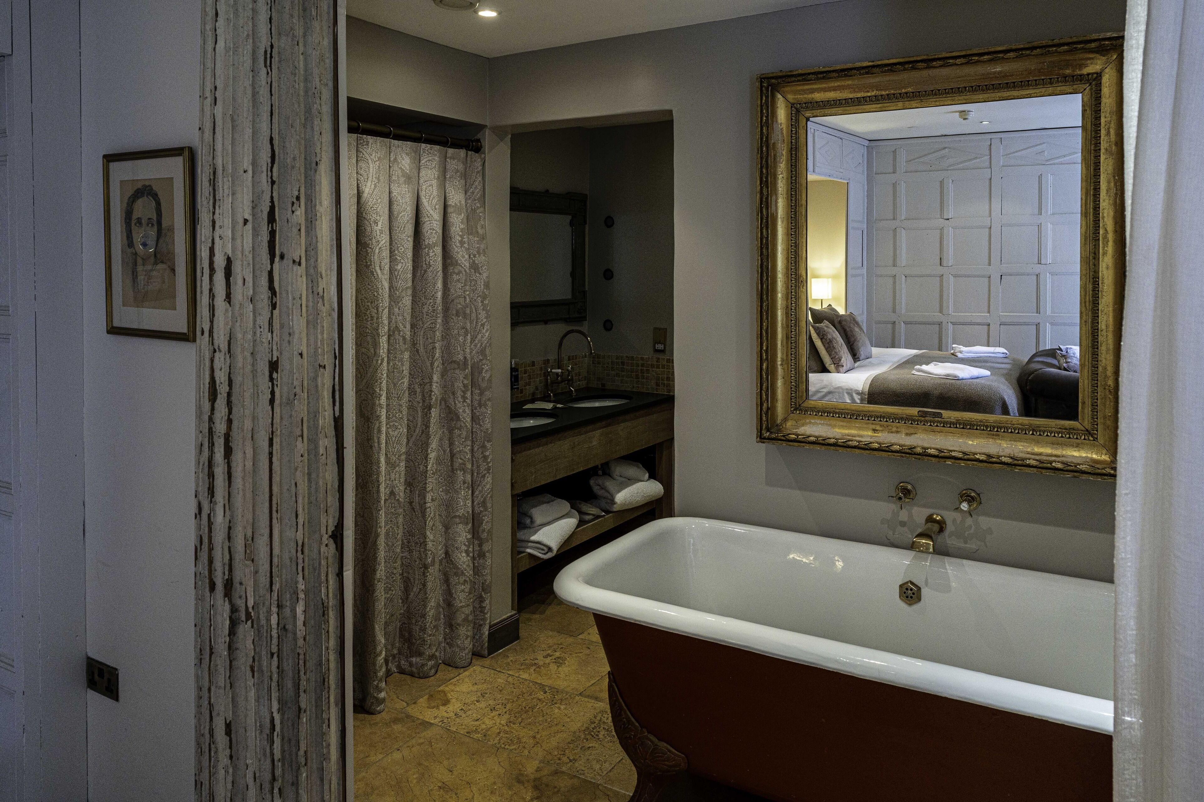 A bathroom with a bathtub, a sink, a mirror, and a shower curtain.