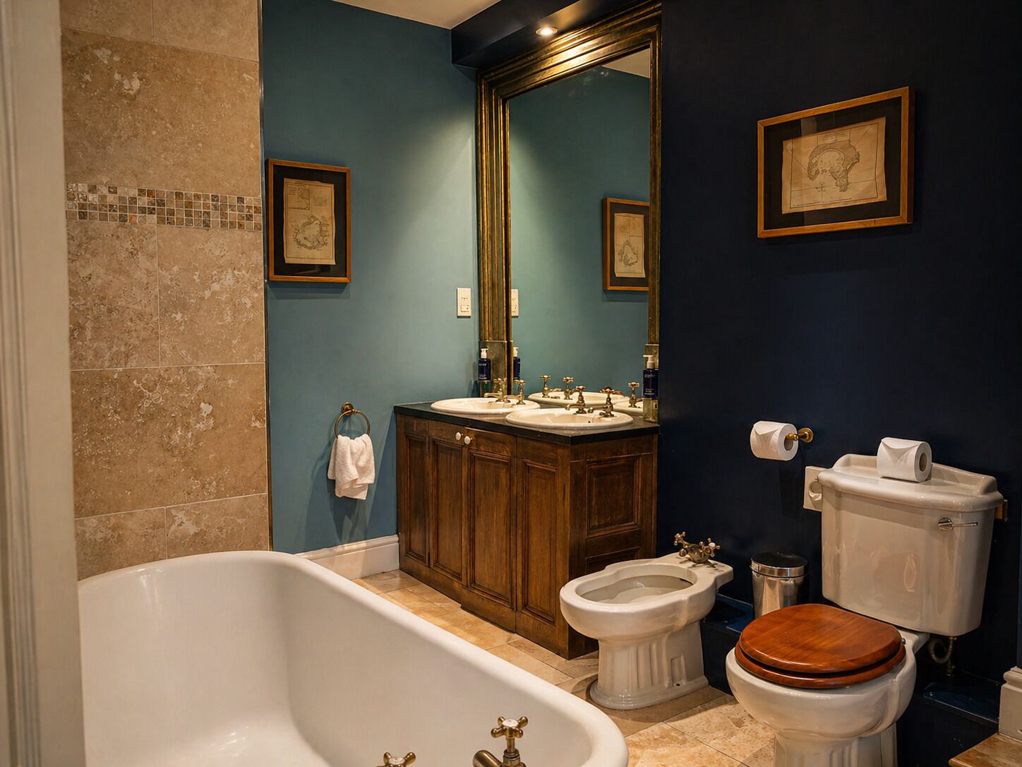 A bathroom with a bathtub, two sinks, a bidet, and a toilet.