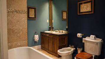 A bathroom with a bathtub, two sinks, a bidet, and a toilet.
