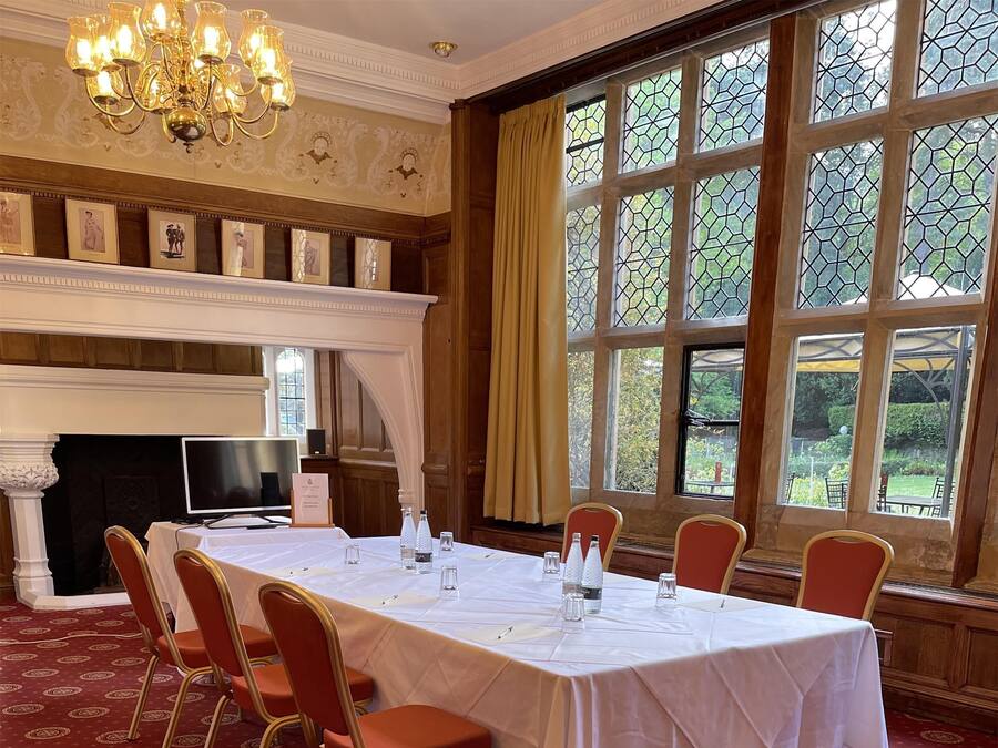 Un comedor formal con una mesa larga, alfombra estampada roja y una chimenea.
