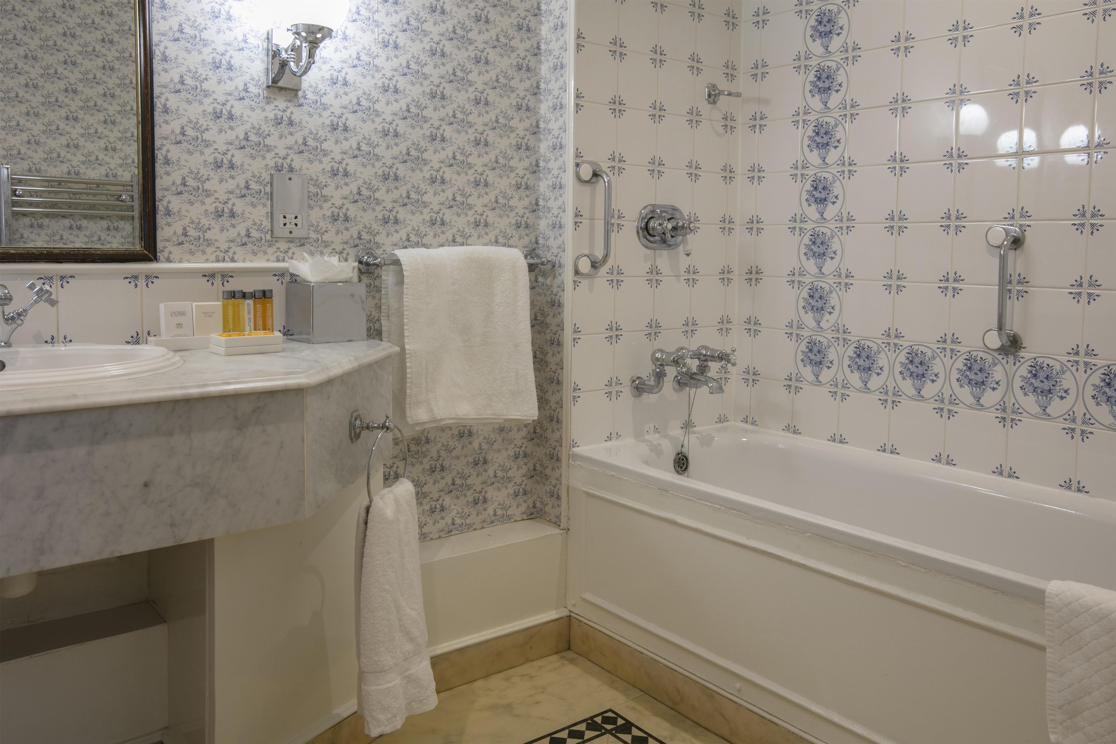 Un baño con lavamanos de mármol, bañera y zona de ducha.