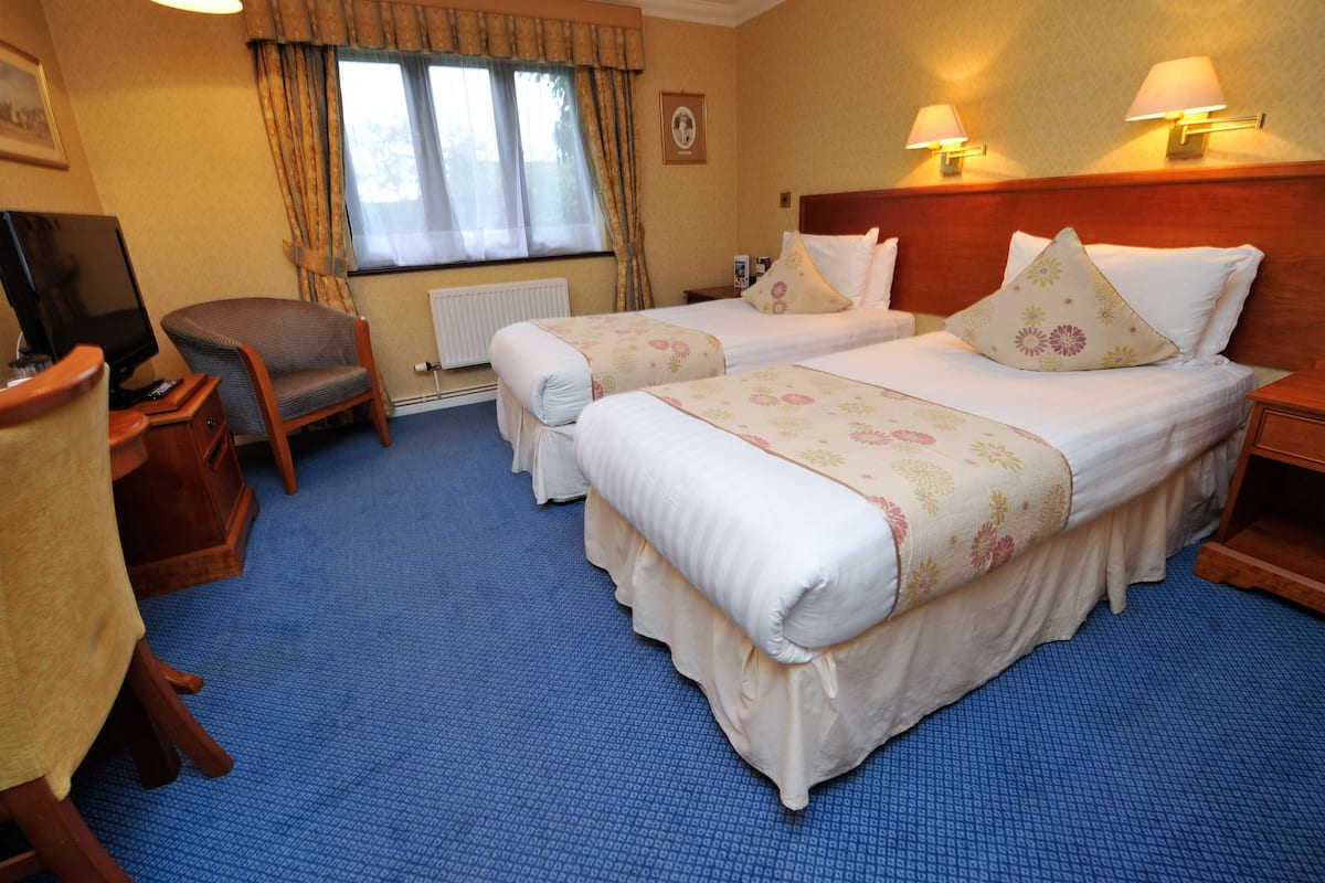 Een hotelkamer met twee bedden, een bureau met een televisie en een stoel.