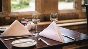 Una mesa de comedor dispuesta con un mantel doblado, dos copas de vino y un tenedor.