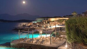 A coastal resort with outdoor seating, a pool, and a view of the sea and mountains. - St. Nicolas Bay Resort Hotel & Villas (Agios Nikolaos)