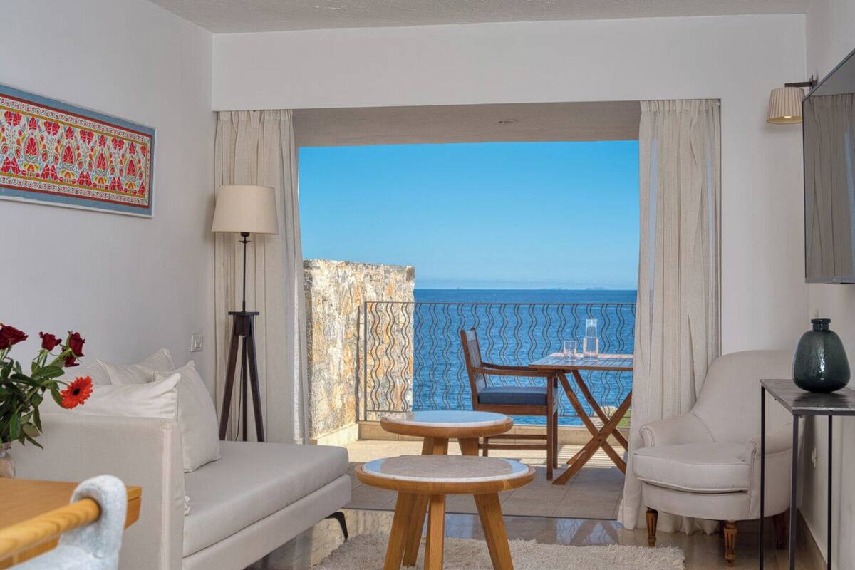 A room with a balcony, a sofa, a table, and a chair.