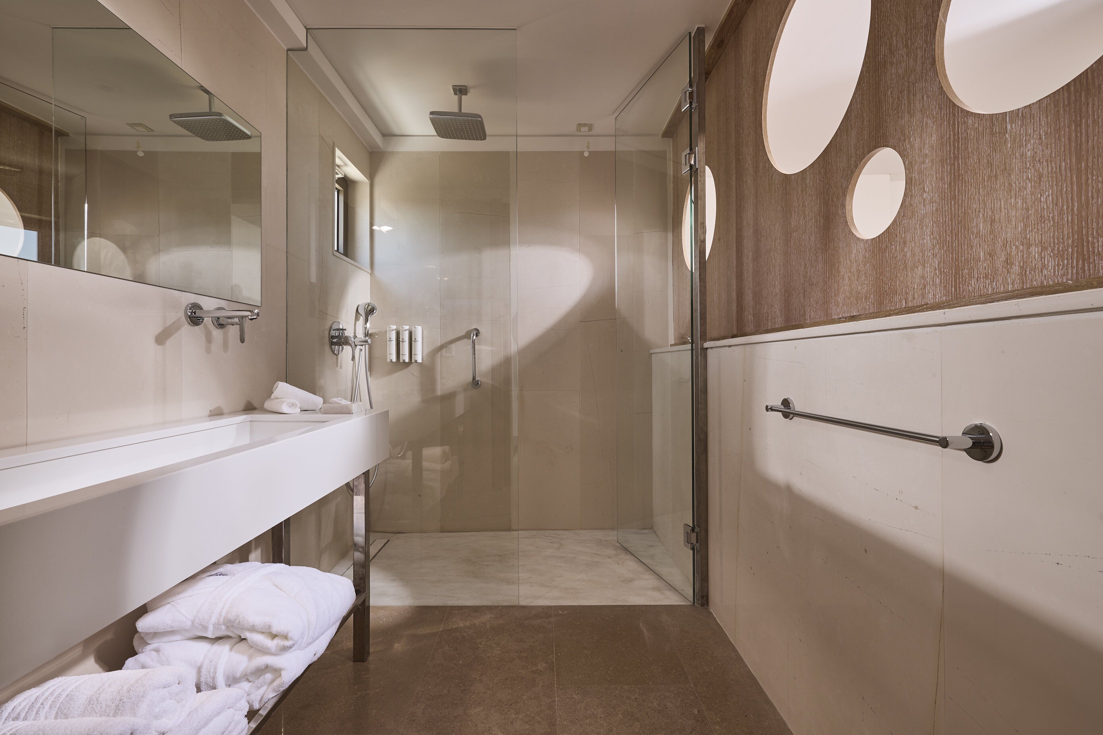 Un baño moderno con ducha envuelta en vidrio, un espejo grande y un perchero para toallas.
