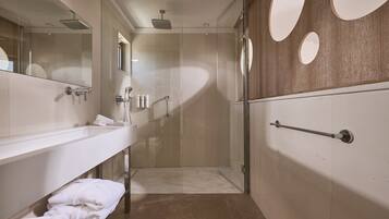 Un baño moderno con ducha envuelta en vidrio, un espejo grande y un perchero para toallas.